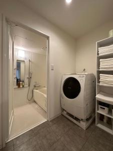 a bathroom with a bath tub and a shower with a mirror at bHOTEL Kaniwasou 201 2BR Apt, Near Itsukushima Shrine, For 12 Ppl in Hatsukaichi