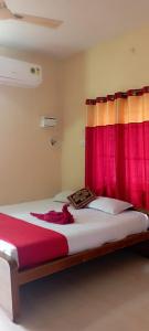 a bedroom with a bed with a red curtain at Ahobila Delux Homes in Tiruchchirāppalli