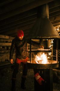 un hombre cocinando comida en un horno con llamas en Aurora Igloo Porvoo, en Porvoo