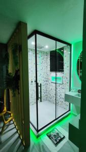 ein Badezimmer mit einer Glasdusche mit grüner Beleuchtung in der Unterkunft Motel Exótico Prime - Próximo GRU Aeroporto in Itaquaquecetuba