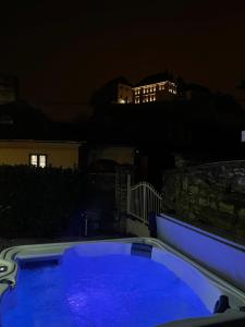 una piscina azul por la noche con un edificio en el fondo en FRIDA Apartman, Exkluzív várpanorámával, a belváros szívében en Veszprém