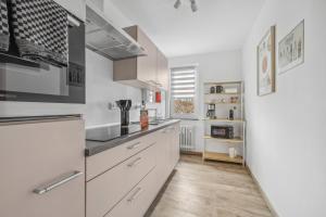 una cocina con armarios blancos y electrodomésticos de acero inoxidable en Amalfi A02 - 2 Zi für 4P - Balkon, smart TV, Boxspringbett, en Kaiserslautern