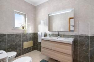 La salle de bains est pourvue d'un lavabo, de toilettes et d'un miroir. dans l'établissement Casa Mar-a-vila, à Olhão