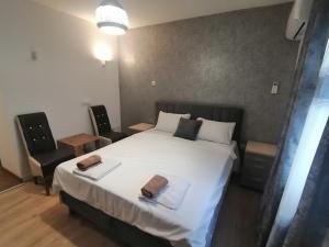 una camera da letto con un grande letto bianco e due sedie di Apartman Ika 2N a Kraljevo