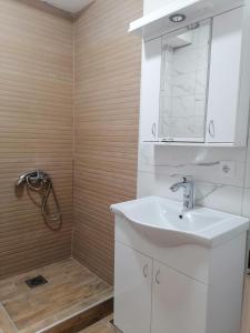 a white bathroom with a sink and a shower at Apartmani Mia in Kraljevo