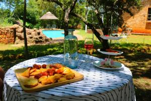 a table with a plate of food and a bottle of wine at Tranquil Mountain Cottage :Hikes/Boma/Animals/Pool in Magaliesburg