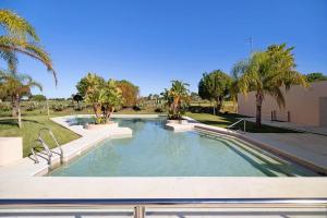 una piscina en un parque con palmeras en Apartamento Villanueva Golf en Puerto Real