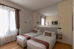 a hotel room with two beds and a window at Aiello Rooms - San Babila in Milan