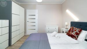 a white bedroom with a bed with a blue headboard at Apartamenty Good Time - Ale Widok! in Szklarska Poręba