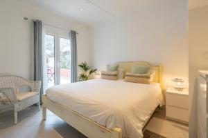a white bedroom with a bed and a balcony at Campo & Mar Apartments in Porto Moniz