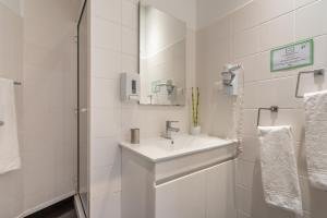 Baño blanco con lavabo y espejo en Campo & Mar Apartments, en Porto Moniz