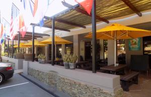 um restaurante com guarda-sóis amarelos e mesas de madeira em Barrydale Karoo Lodge - Boutique Hotel em Barrydale