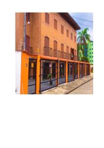 un edificio naranja con una valla delante en Apartamento para Temporada Ubatuba, en Ubatuba