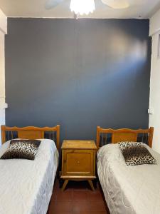 two beds in a room with a blue wall at 3260HOSTEL in Concepción del Uruguay