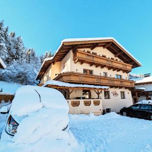 una casa cubierta de nieve con un coche aparcado delante de ella en Alpenchalet Almrose en Auffach