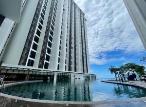 a large building with a swimming pool in front of the ocean at The Nest at The Shore KK CBD Seaview with Balcony in Kota Kinabalu