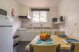 a kitchen with a table with a bowl of fruit on it at Campo & Mar Apartments in Porto Moniz