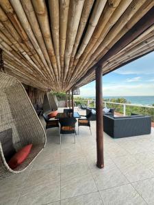 a patio with a wooden roof with chairs and a table at Peri-Peri Divers B&B Morrungulo in Cabo Nhabacal