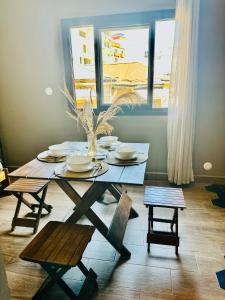 una mesa de comedor con platos y sillas y una ventana en NH (Njato Hôtel), en Antananarivo