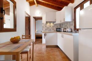 a kitchen with white cabinets and a wooden table at La Casita de Abuela Paula in Valleseco