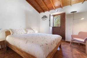 a bedroom with a bed and a chair and a window at La Casita de Abuela Paula in Valleseco