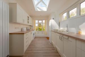 a kitchen with white cabinets and a skylight at Family Beach House 200m to Sea 5 min to Tenby Town Centre in Pembrokeshire