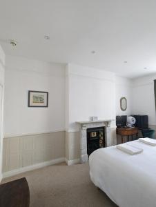 a white bedroom with a bed and a fireplace at The Dulwich in Cheltenham