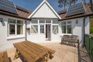 eine Terrasse mit einer Holzbank und ein Haus mit Sonnenkollektoren in der Unterkunft Family Beach House 200m to Sea 10min to Centre in Pembrokeshire