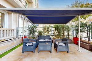 eine Terrasse mit Stühlen und einem blauen Baldachin in der Unterkunft Loft Victor Hugo 73 Fshh in Nizza