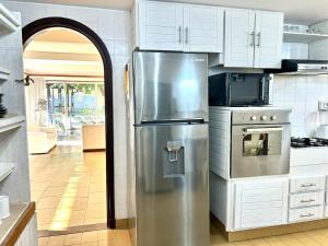 uma cozinha com um frigorífico de aço inoxidável e armários brancos em Beautiful Chalet Punta del Este em Punta del Este