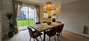 a dining room table with chairs and a large window at Bunratty west Townhouse in Bunratty