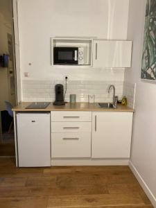 a white kitchen with a sink and a microwave at Studio N 2 cosy hypercentre, rue Saint Nicolas in Rouen +1 photo