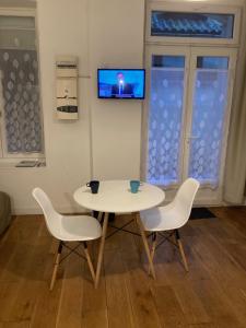 a white table and chairs with a tv on a wall at Studio N 2 cosy hypercentre, rue Saint Nicolas in Rouen