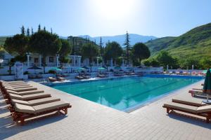 a swimming pool with chaise lounges and chairs at Edva Resort in Vlorë