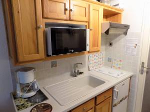 eine Küche mit einer Spüle und einer Mikrowelle in der Unterkunft La Palmyre - CHARMANTE VILLA MITOYENNE avec TERRASSE CLOSE in Les Mathes