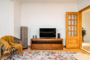una sala de estar con TV en un centro de entretenimiento de madera en Akicity Santa Apolónia Green, en Lisboa
