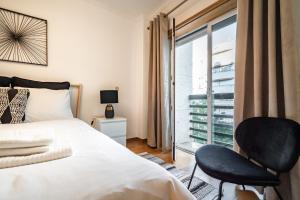 um quarto com uma cama, uma cadeira e uma janela em Akicity Santa Apolónia Green em Lisboa