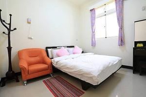 um quarto com uma cama e uma cadeira laranja em 成功民宿 KM Bed and Breakfast em Jinhu