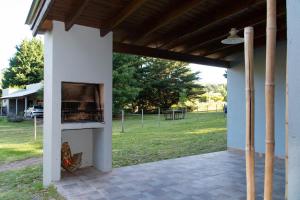 un patio al aire libre con horno de pizza y vistas a un parque en Cabañas El Viejo Sauce en Tandil