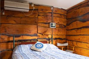 1 dormitorio con 1 cama en una pared de madera en Cabañas El Viejo Sauce en Tandil