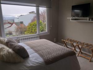 um quarto com uma cama e uma grande janela em Departamento completo en San Carlos de Bariloche, Argentina em San Carlos de Bariloche