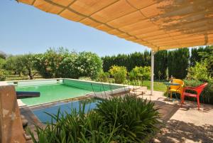 a swimming pool with a table and chairs under an umbrella at Selva - 4101 Mallorca in Selva