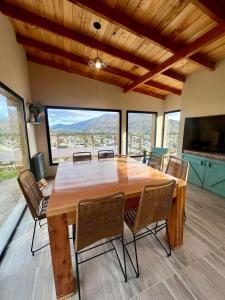 ein großer Holztisch und Stühle in einem Zimmer mit Fenstern in der Unterkunft Refugio del Pescador in Esquel