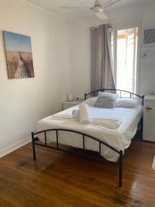 una camera da letto con un letto con lenzuola bianche e una finestra di Civic Guesthouse a Townsville