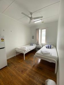 a room with two beds and a ceiling fan at Civic Guesthouse in Townsville