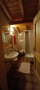 a bathroom with a sink and a tub and a toilet at Pizzeria Marmolada Camere in Sottoguda