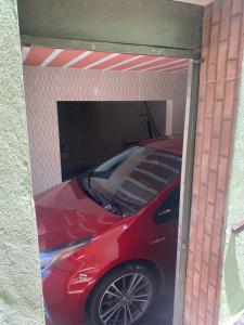 czerwony samochód zaparkowany w garażu w obiekcie CASA DE FÉRIAS BH w mieście Belo Horizonte