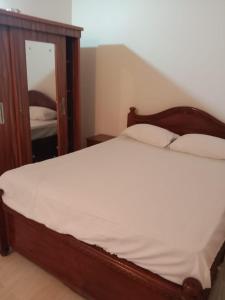 a bed with a wooden frame and a mirror at RED HOUSE - AGONDA BEACH in Agonda