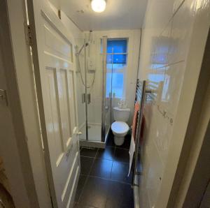 a small bathroom with a toilet and a shower at Rooms Anfield- 5 mins from LFC in Liverpool