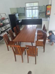 a wooden table and chairs with a child sitting on the floor at Nha Trang Riverside Villa in Nha Trang